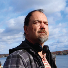 Man standing outside on a sunny day, looking at something in the distance.