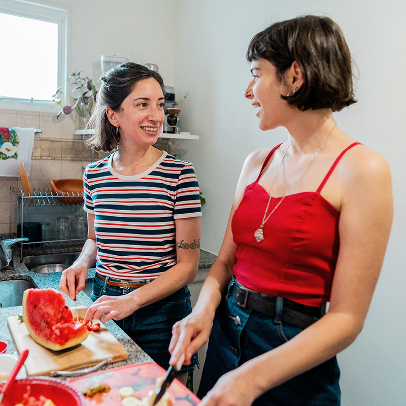 Female friends talking and preparing fruits in the kitchen